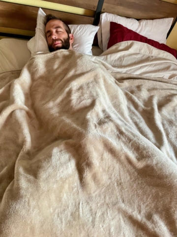 Man laying in bed cozily with covers