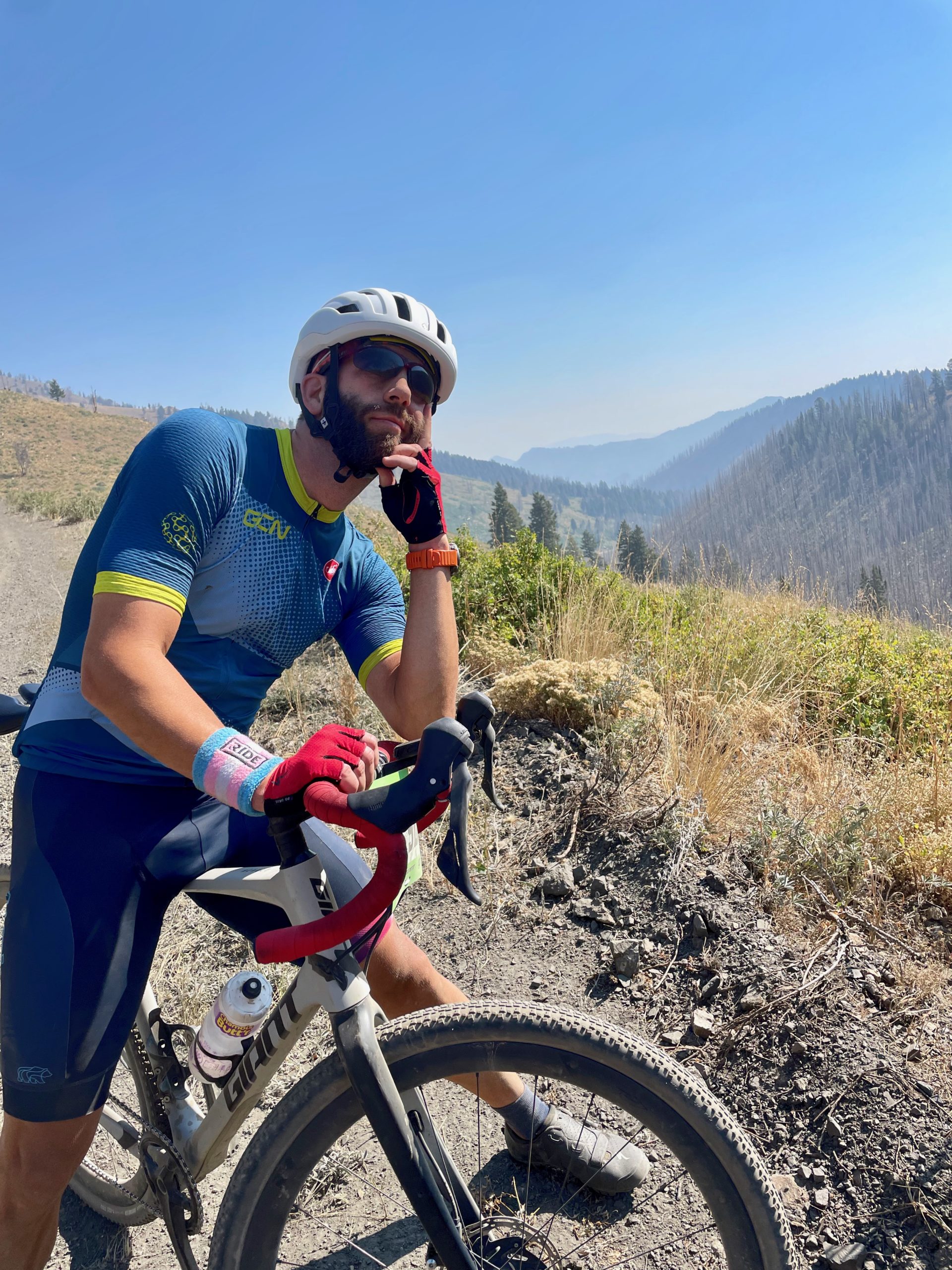Man in a relaxed position poses on bike with mountains in the background